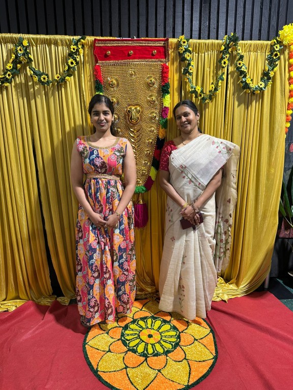 ATCS representatives at the Canberra Malayalee Association Onam 2026 celebrations, standing beside a floral pookalam